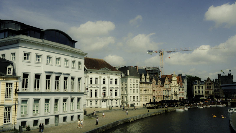 Elegant buildings line a river under a sunny sky.